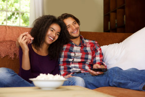 Smiling boyfriend and girlfriend relaxing watching tv